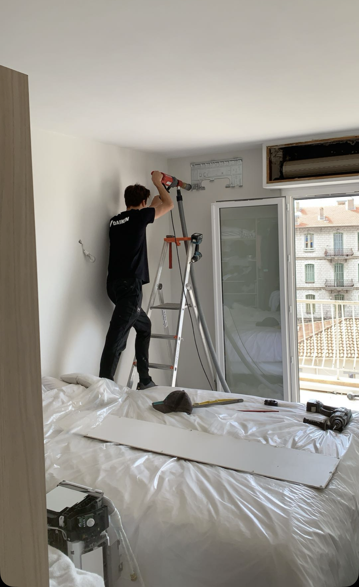 Technicien SARL Cosma installant une climatisation murale